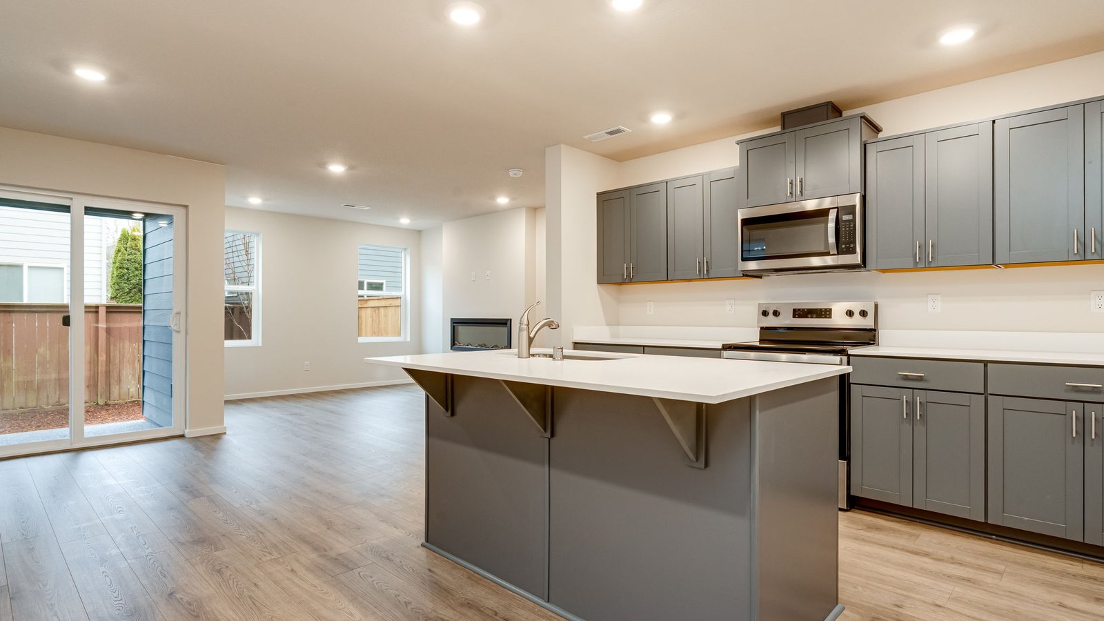 Kitchen with shaker cabinets, quartz counters, stainless steel appliances, pantry, and an island with a breakfast bar
