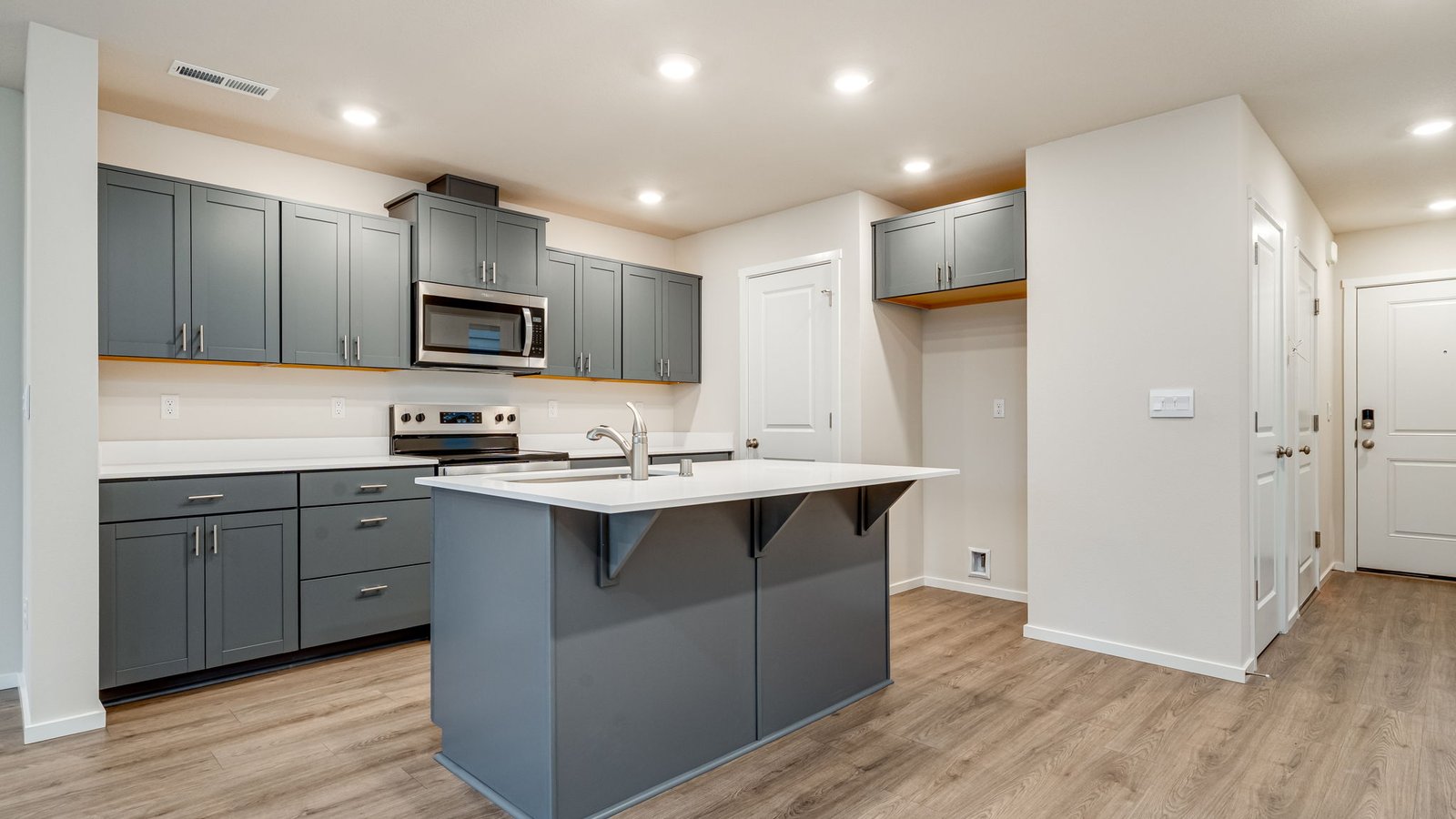 Kitchen with shaker cabinets, quartz counters, stainless steel appliances, pantry, and an island with a breakfast bar