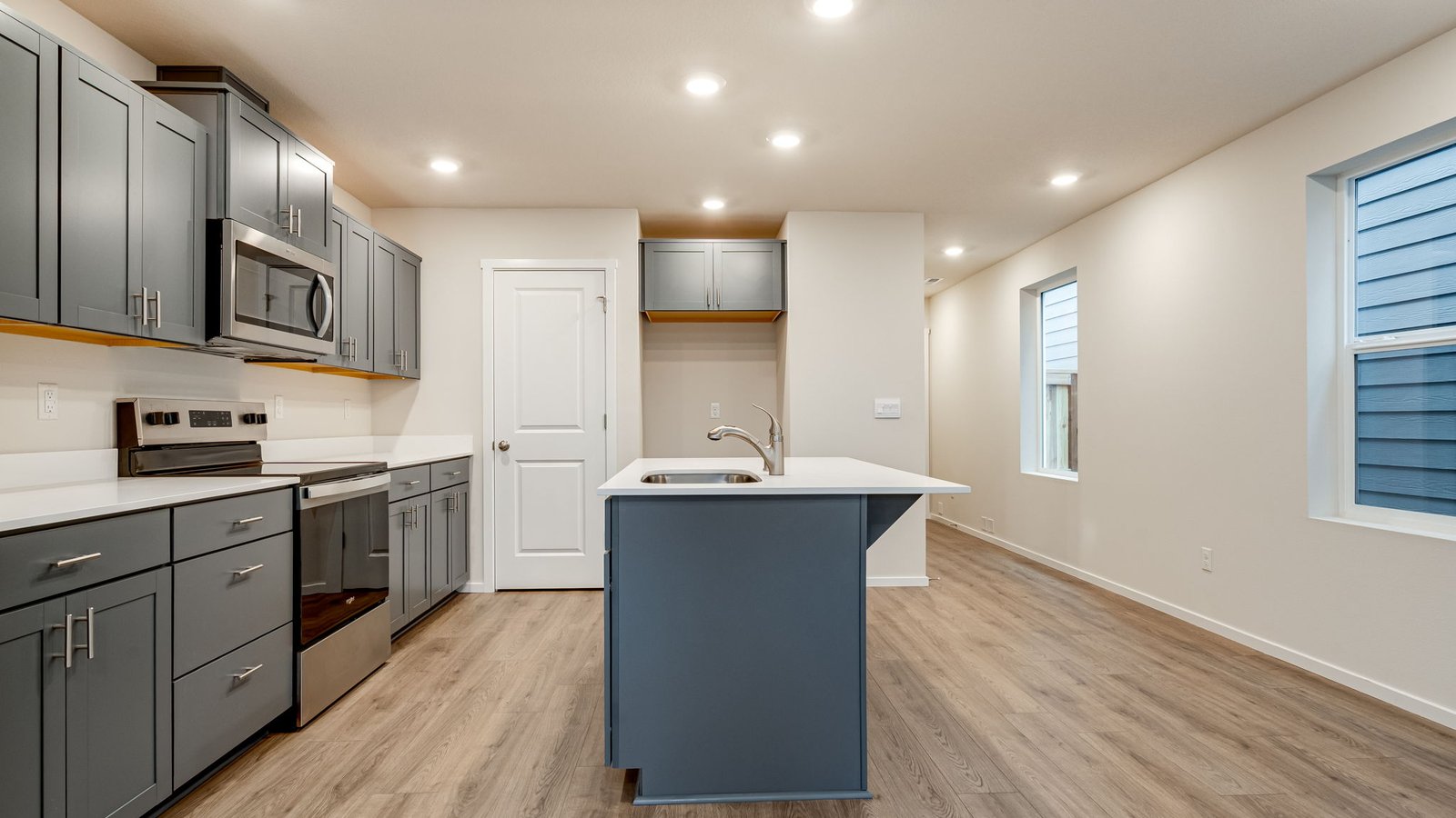 Kitchen with shaker cabinets, quartz counters, stainless steel appliances, pantry, and an island with a breakfast bar