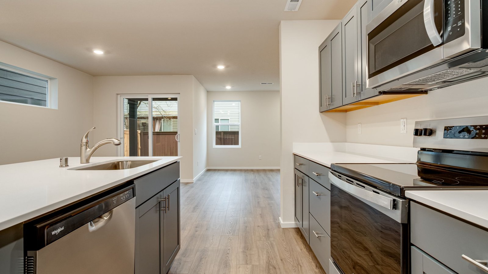 Kitchen with shaker cabinets, quartz counters, stainless steel appliances, pantry, and an island with a breakfast bar
