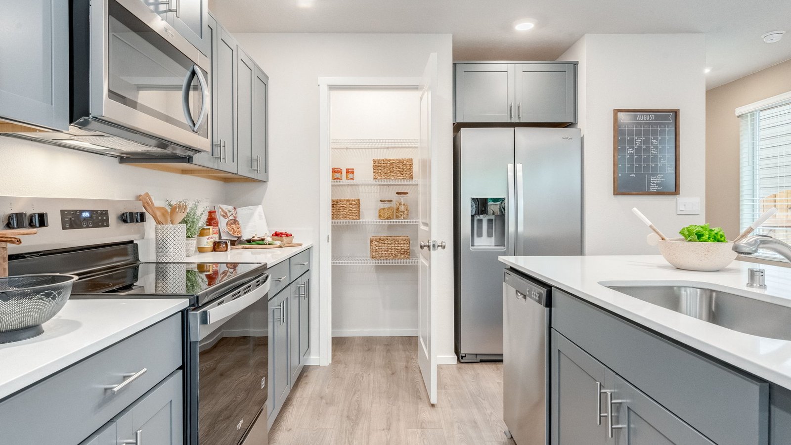 Kitchen with shaker cabinets, quartz counters, stainless steel appliances, pantry, and an island with a breakfast bar