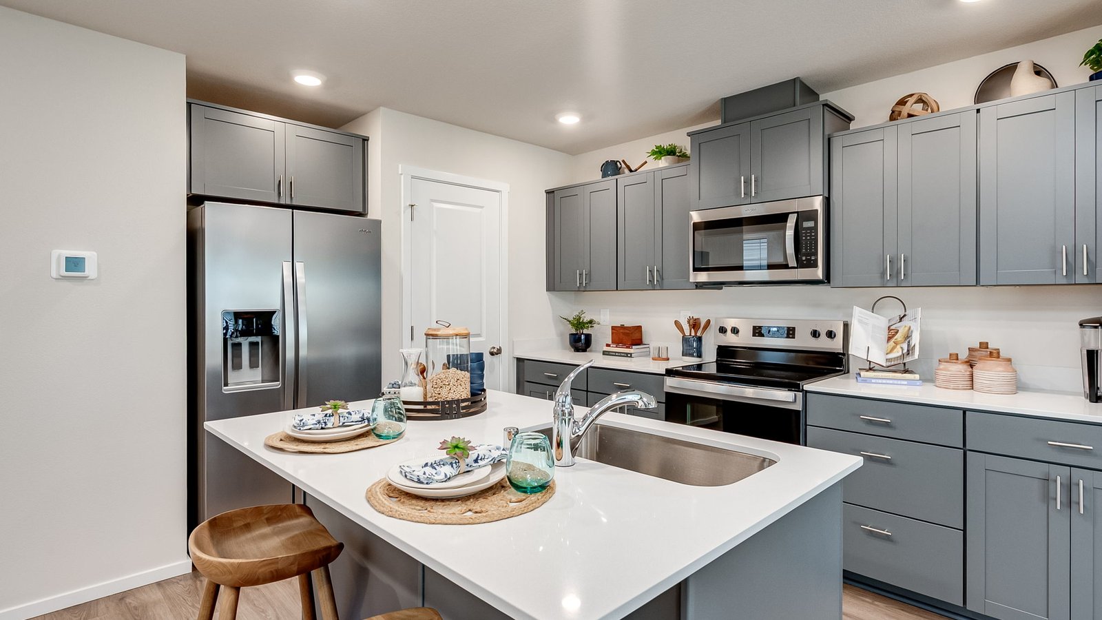Kitchen with shaker cabinets, quartz counters, stainless steel appliances, pantry, and an island with a breakfast bar