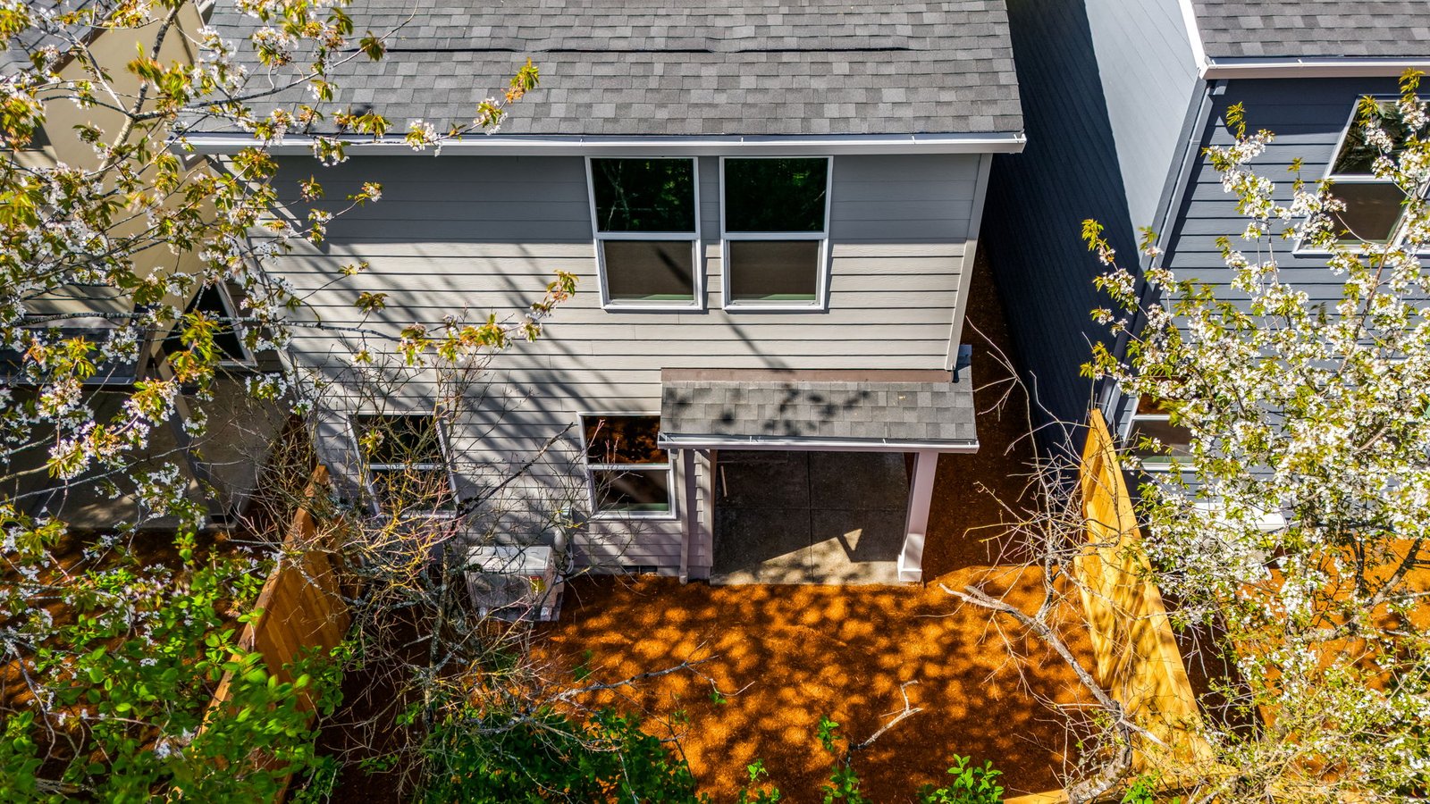 fully fenced backyard with bark chips and a patio