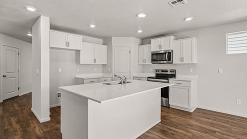 Kitchen with shaker cabinets, quartz counters, stainless steel appliances, pantry, and an island with a breakfast bar