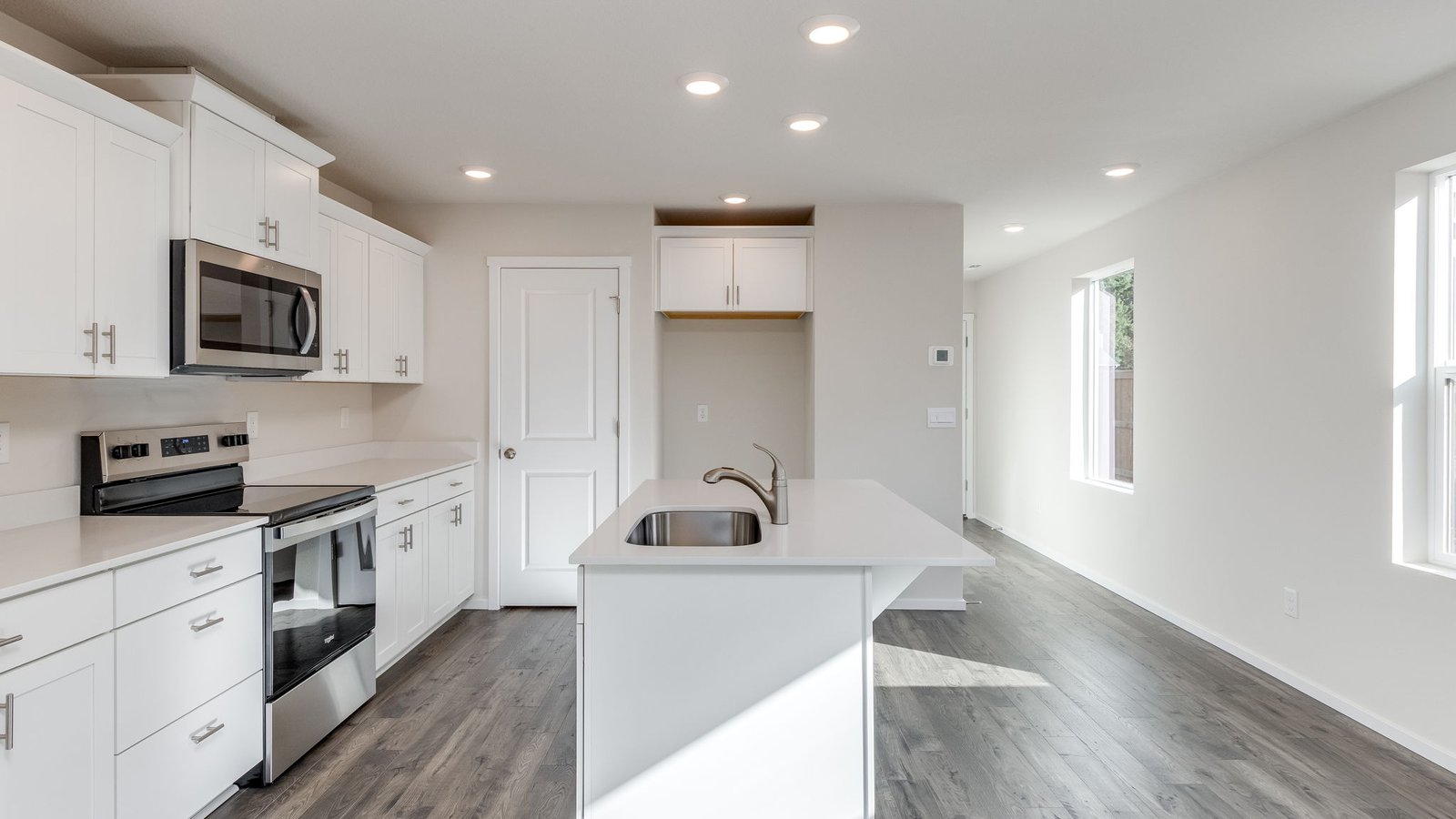Kitchen with shaker cabinets, quartz counters, stainless steel appliances, pantry, and an island with a breakfast bar