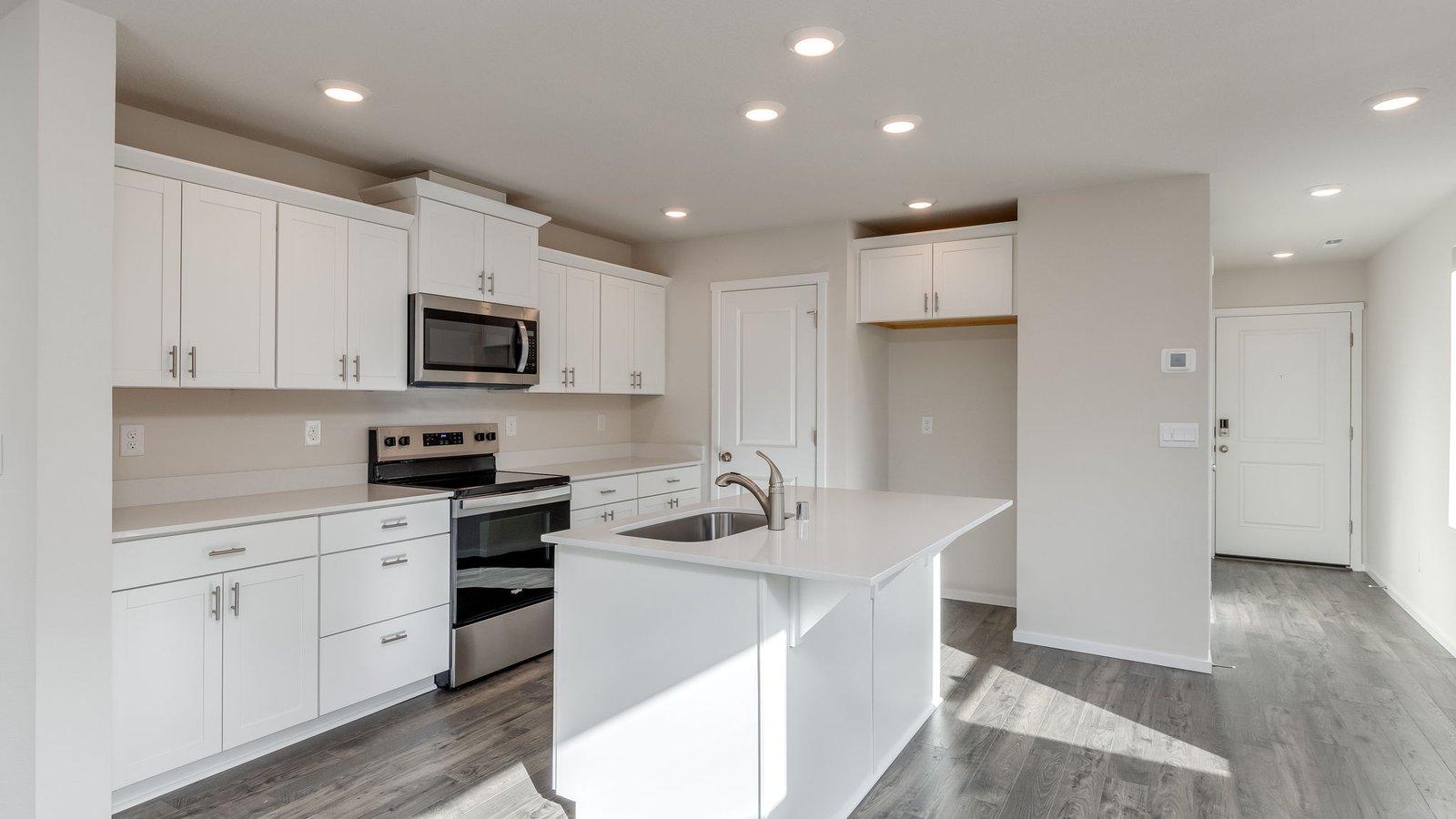 Kitchen with shaker cabinets, quartz counters, stainless steel appliances, pantry, and an island with a breakfast bar