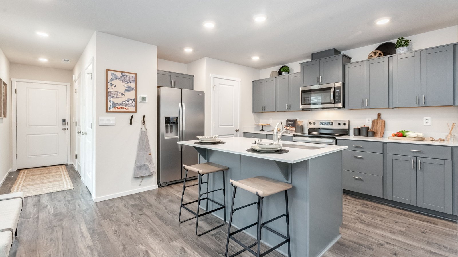 Kitchen with shaker cabinets, quartz counters, stainless steel appliances, pantry, and an island with a breakfast bar