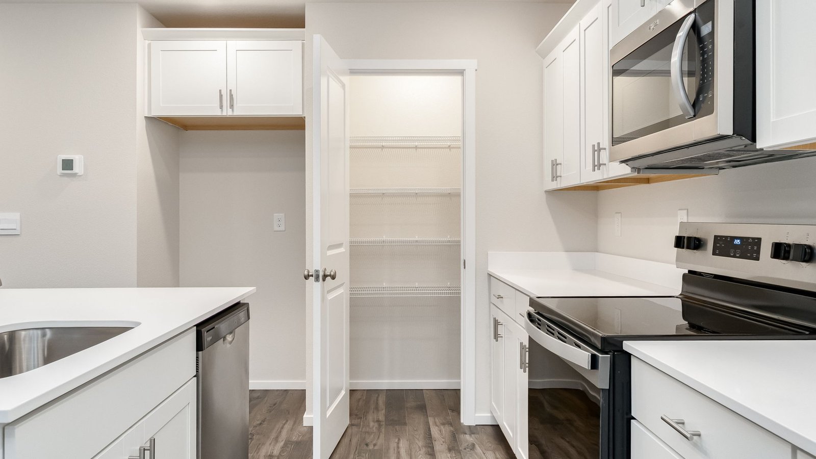 Kitchen with shaker cabinets, quartz counters, stainless steel appliances, pantry, and an island with a breakfast bar