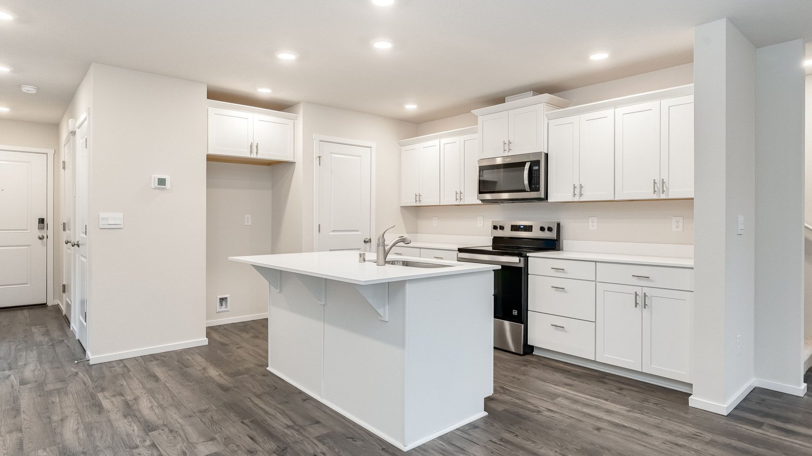 Kitchen with shaker cabinets, quartz counters, stainless steel appliances, pantry, and an island with a breakfast bar