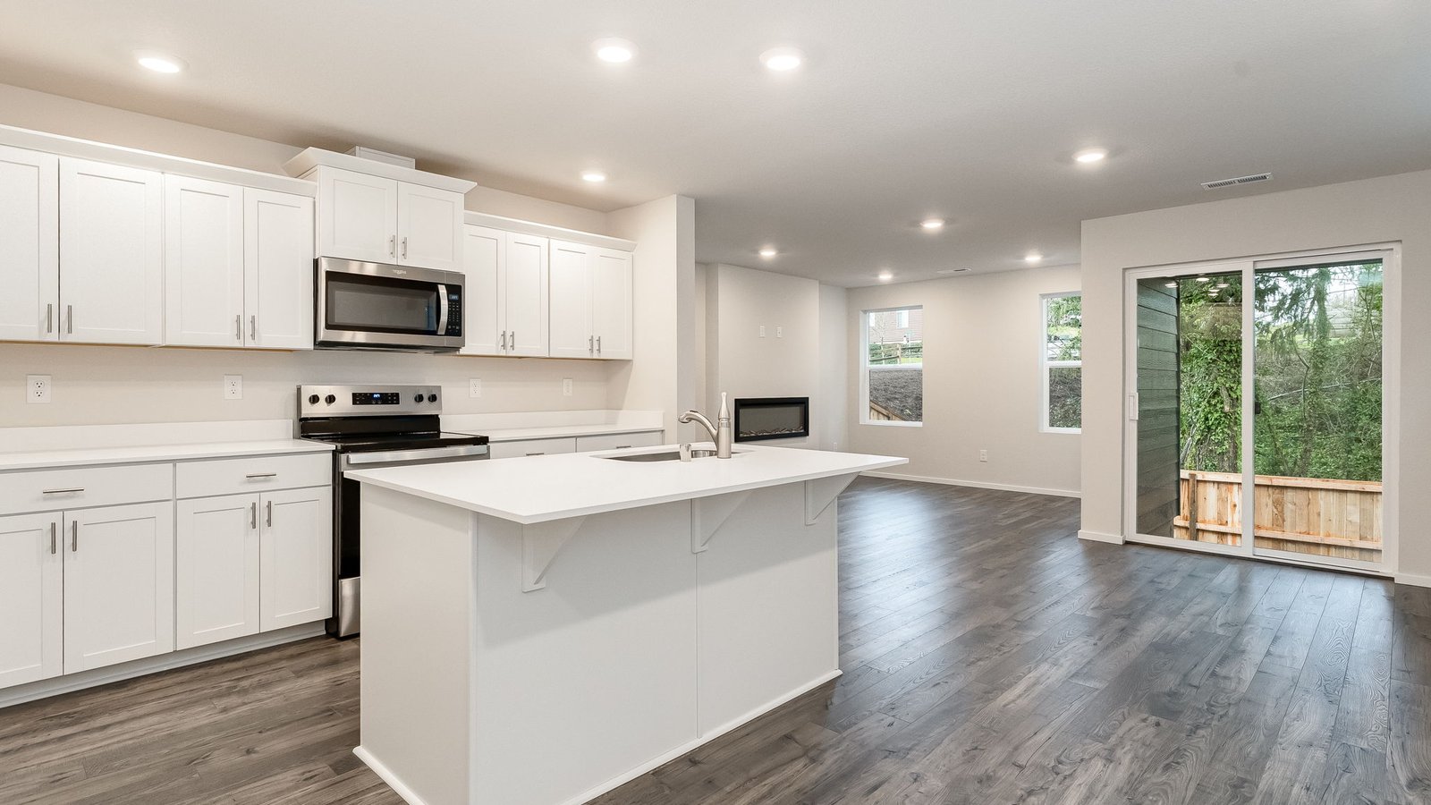 Kitchen with shaker cabinets, quartz counters, stainless steel appliances, pantry, and an island with a breakfast bar