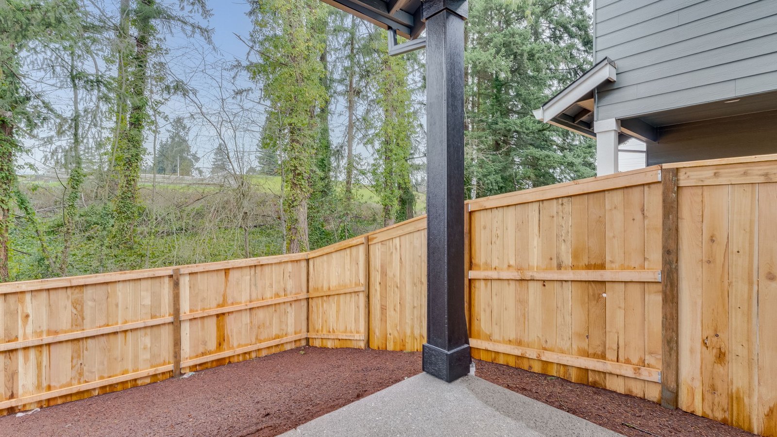 fully fenced backyard with sod lawn and a patio