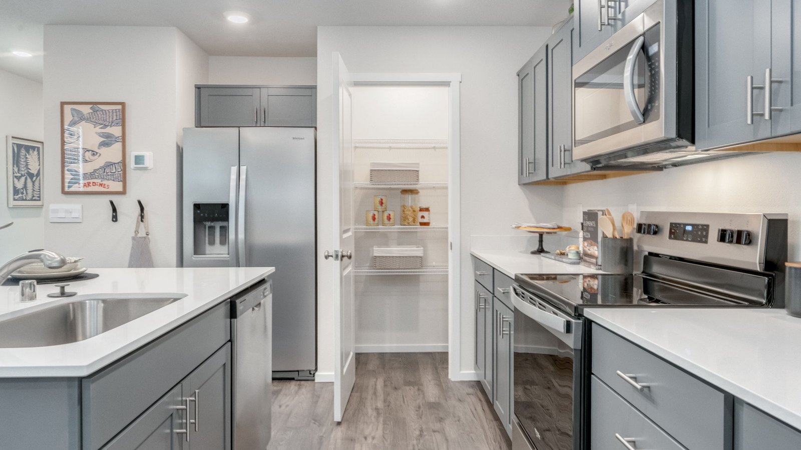 Kitchen with shaker cabinets, quartz counters, stainless steel appliances, pantry, and an island with a breakfast bar