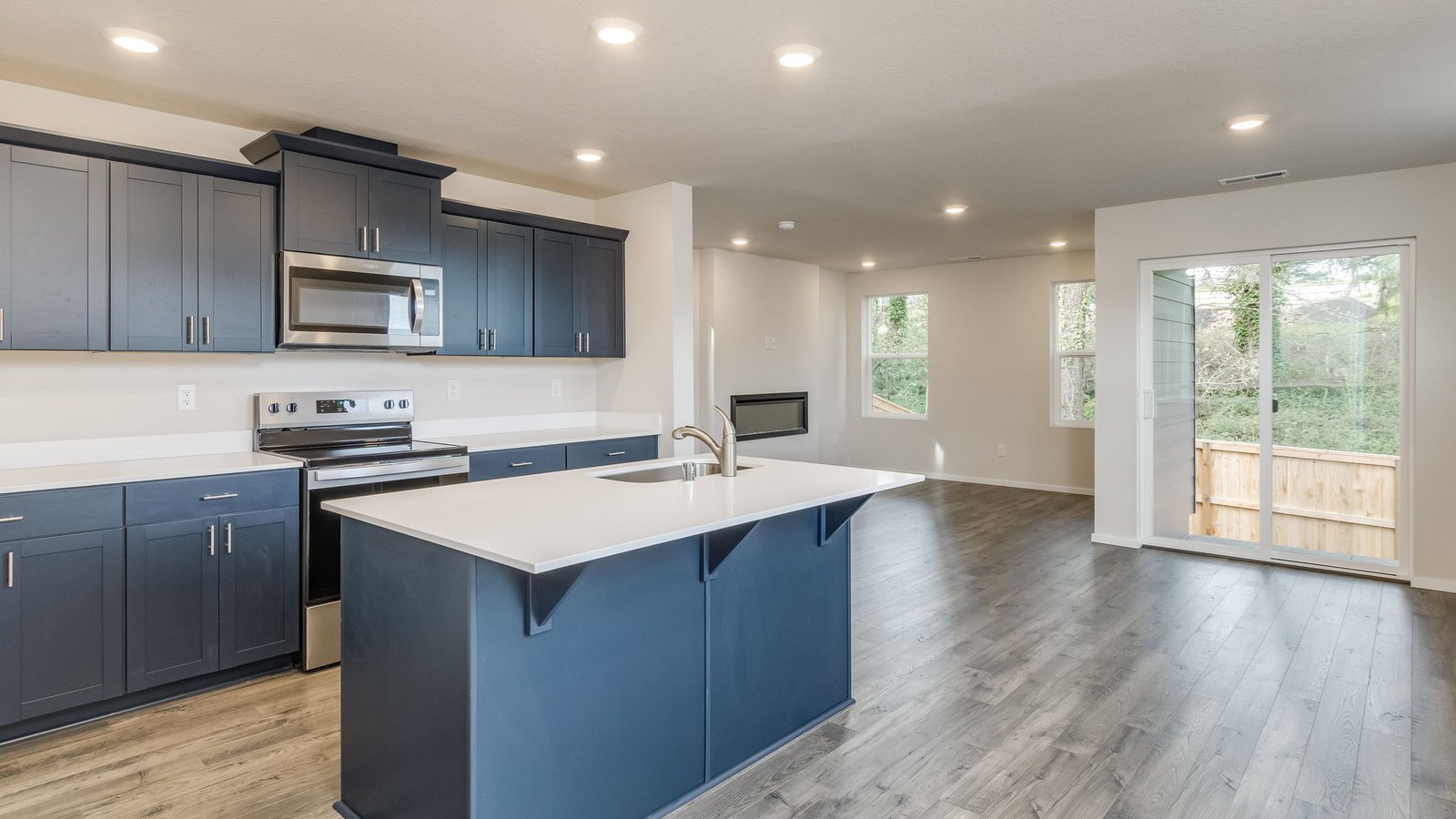 Kitchen with shaker cabinets, quartz counters, stainless steel appliances, pantry, and an island with a breakfast bar