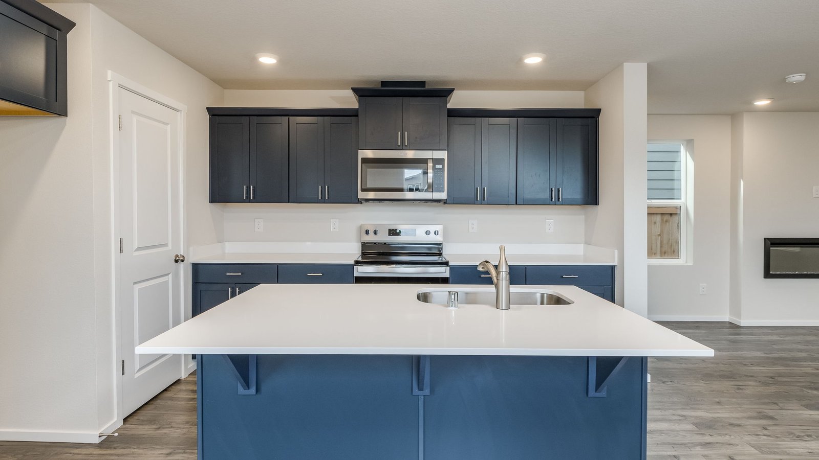 Kitchen with shaker cabinets, quartz counters, stainless steel appliances, pantry, and an island with a breakfast bar