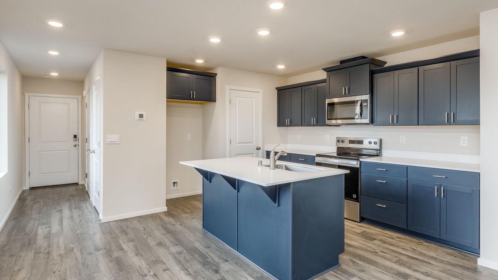 Kitchen with shaker cabinets, quartz counters, stainless steel appliances, pantry, and an island with a breakfast bar