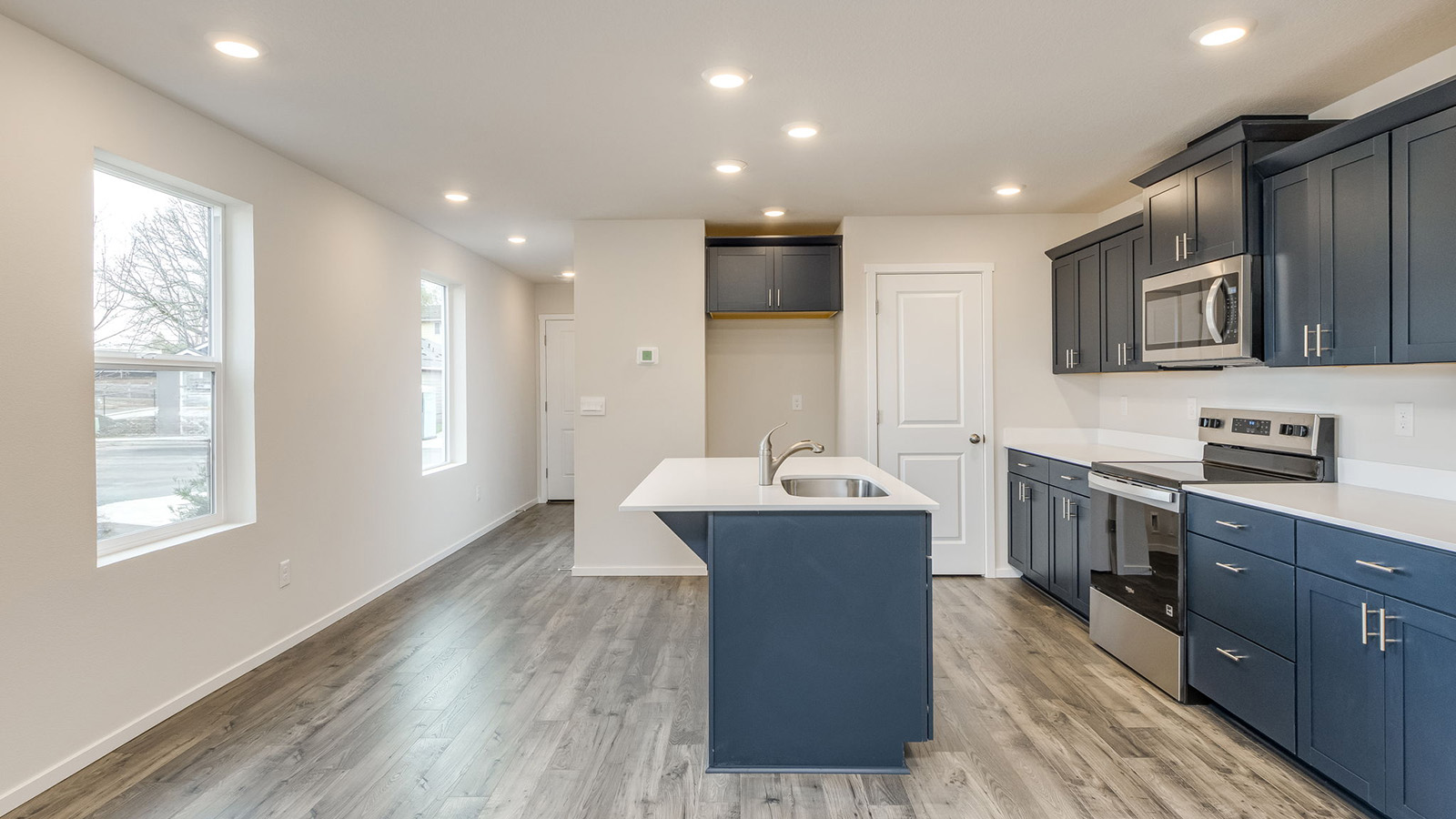Kitchen with shaker cabinets, quartz counters, stainless steel appliances, pantry, and an island with a breakfast bar