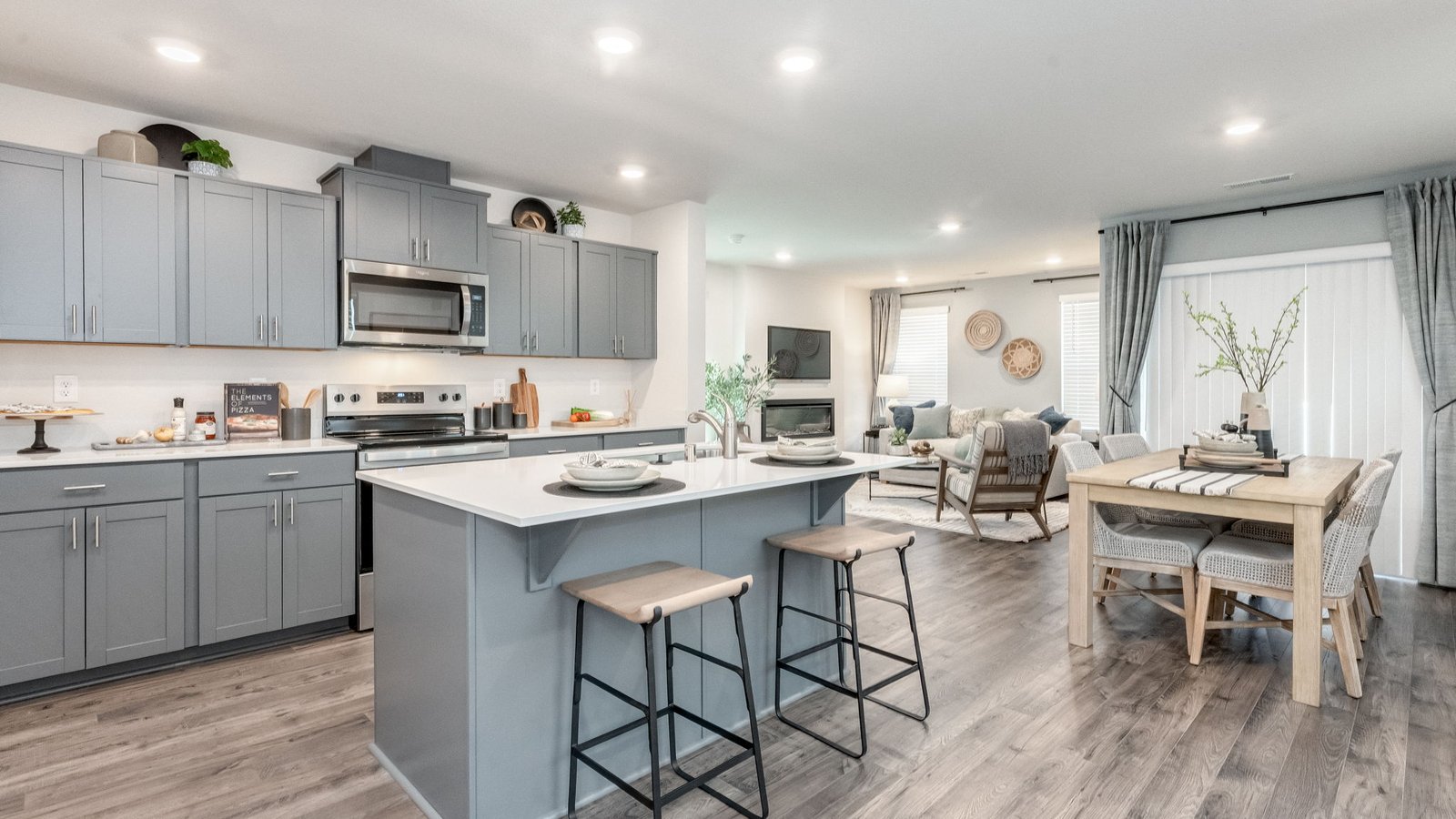 Kitchen with shaker cabinets, quartz counters, stainless steel appliances, pantry, and an island with a breakfast bar