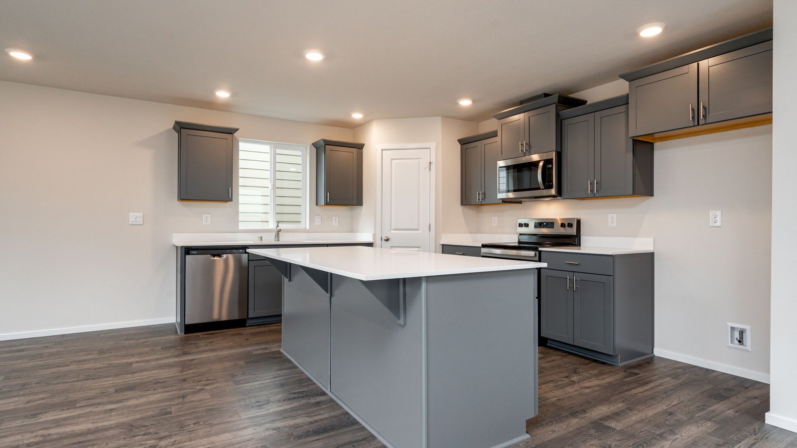 Kitchen with shaker cabinets, quartz counters, stainless steel appliances, pantry, and an island with a breakfast bar