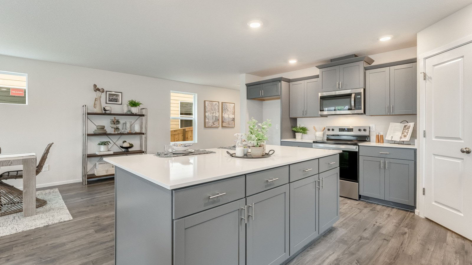 Kitchen with shaker cabinets, quartz counters, stainless steel appliances, pantry, and an island with a breakfast bar