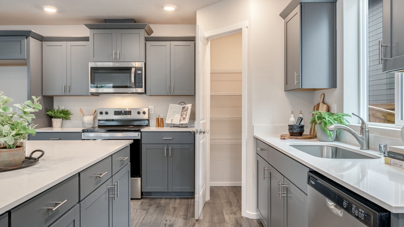 Kitchen with shaker cabinets, quartz counters, stainless steel appliances, pantry, and an island with a breakfast bar