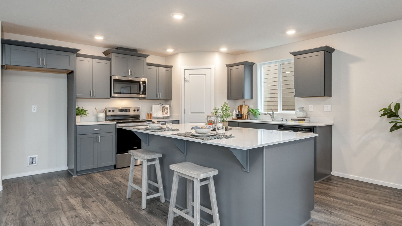 Kitchen with shaker cabinets, quartz counters, stainless steel appliances, pantry, and an island with a breakfast bar
