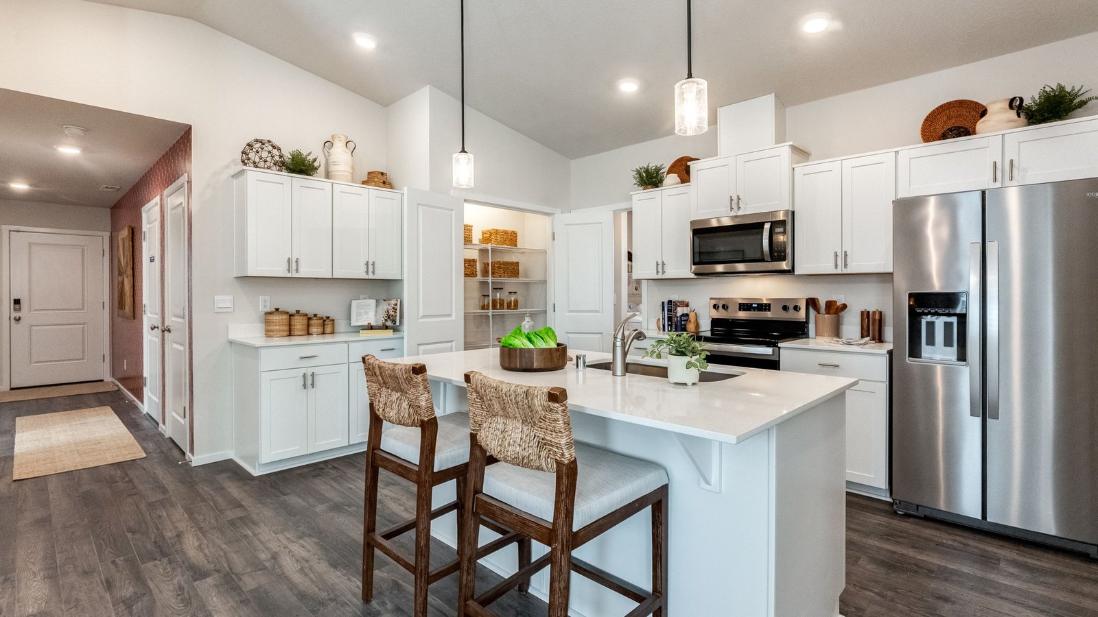 Kitchen with shaker cabinets, quartz counters, stainless steel appliances, pantry, and an island with a breakfast bar