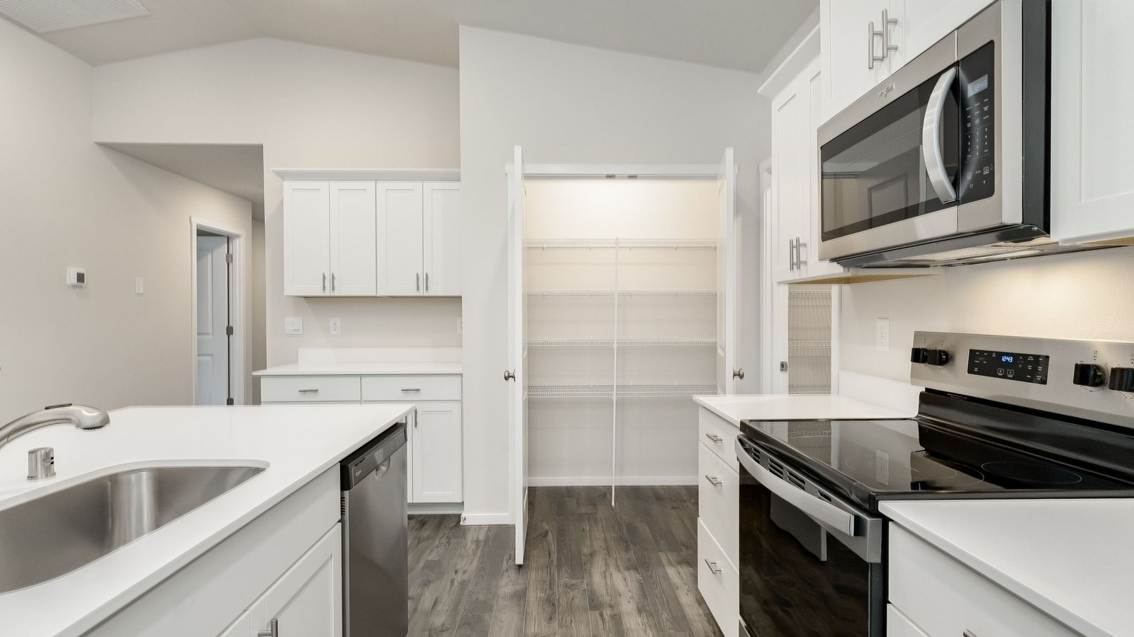 Kitchen with shaker cabinets, quartz counters, stainless steel appliances, pantry, and an island with a breakfast bar