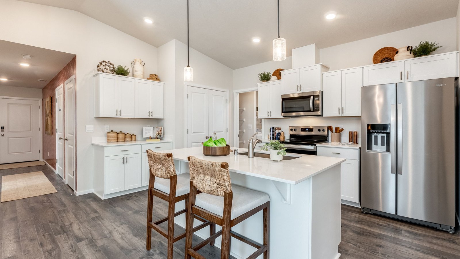 Kitchen with shaker cabinets, quartz counters, stainless steel appliances, pantry, and an island with a breakfast bar
