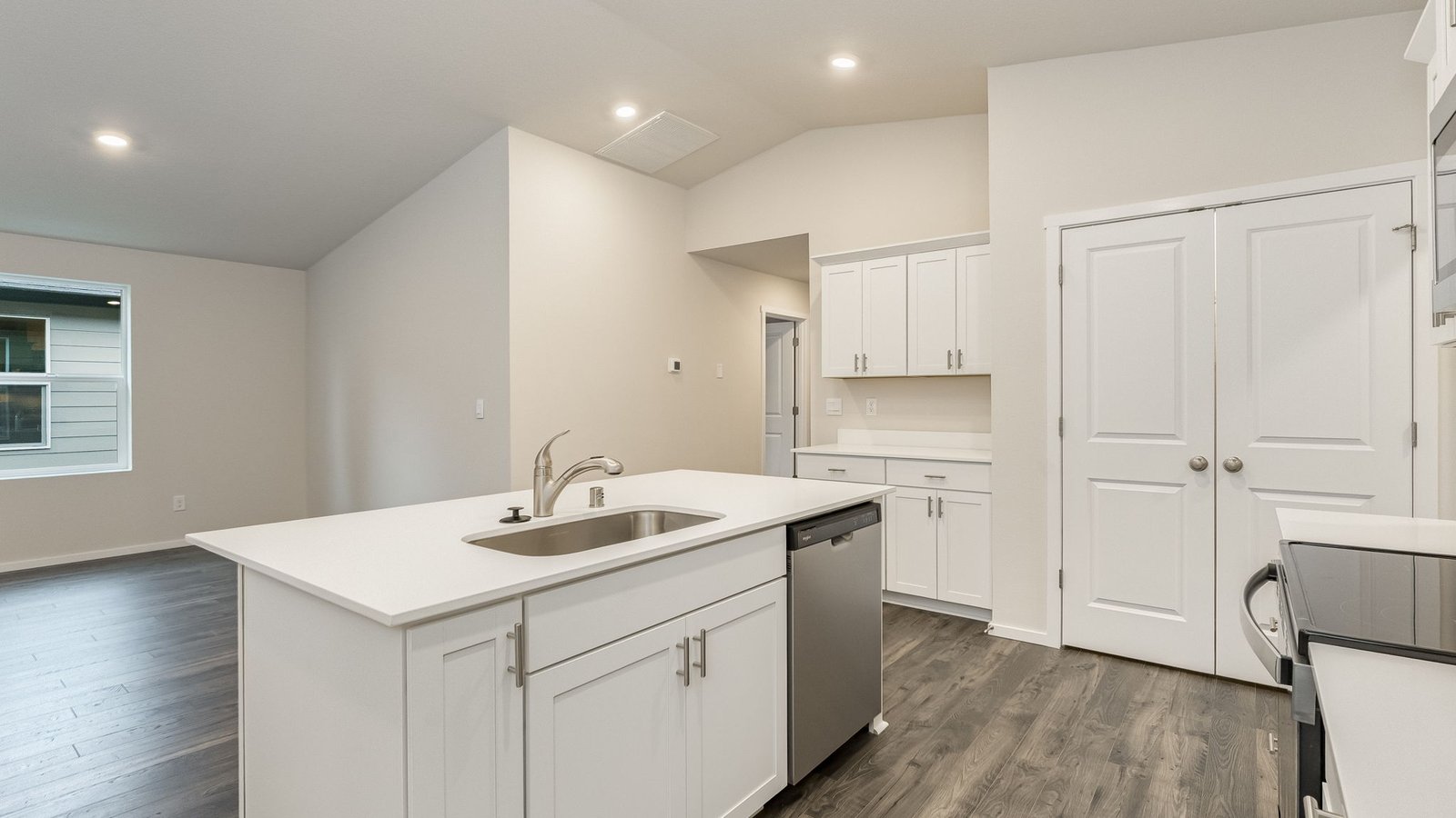 Kitchen with shaker cabinets, quartz counters, stainless steel appliances, pantry, and an island with a breakfast bar
