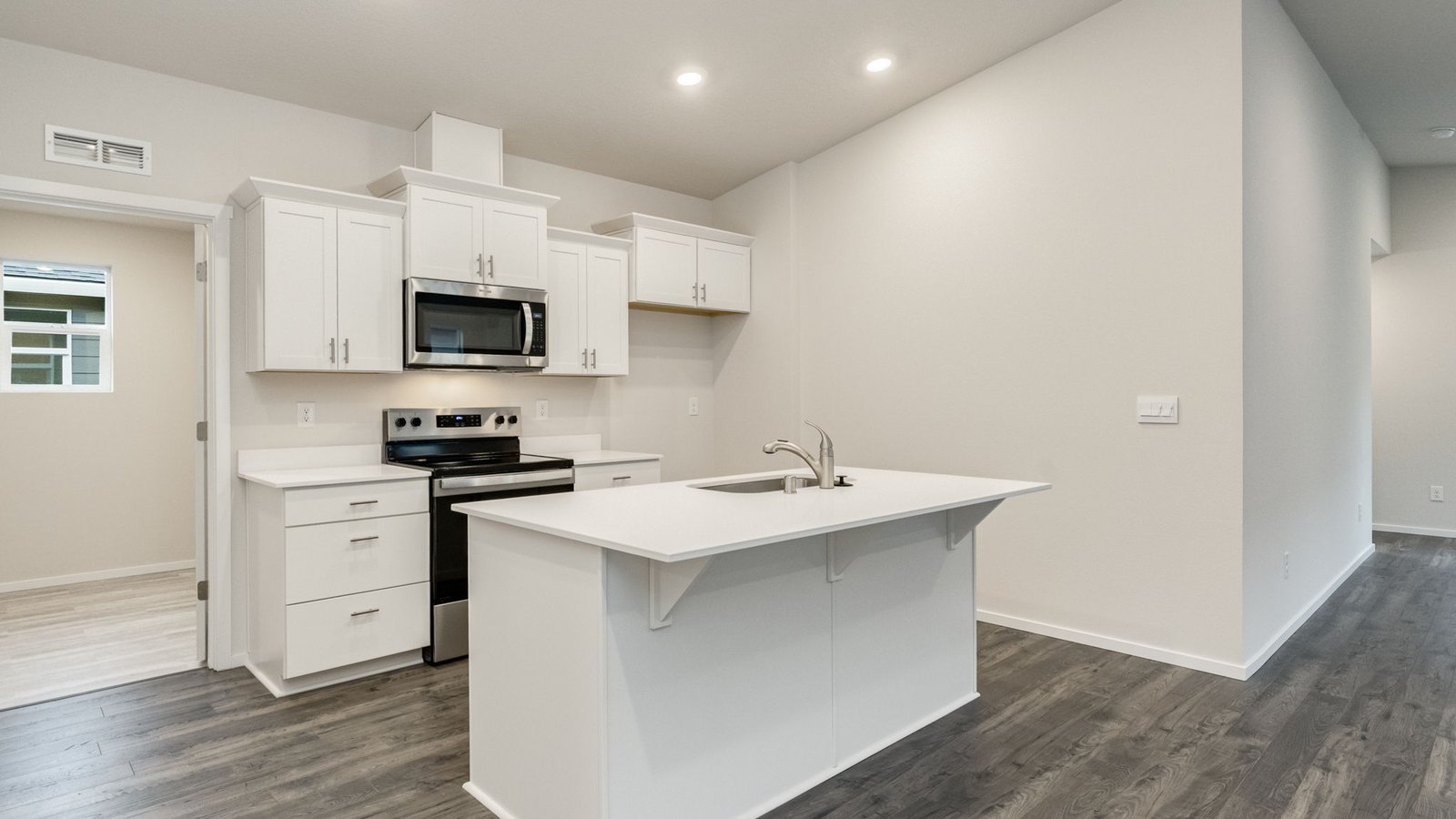 Kitchen with shaker cabinets, quartz counters, stainless steel appliances, pantry, and an island with a breakfast bar