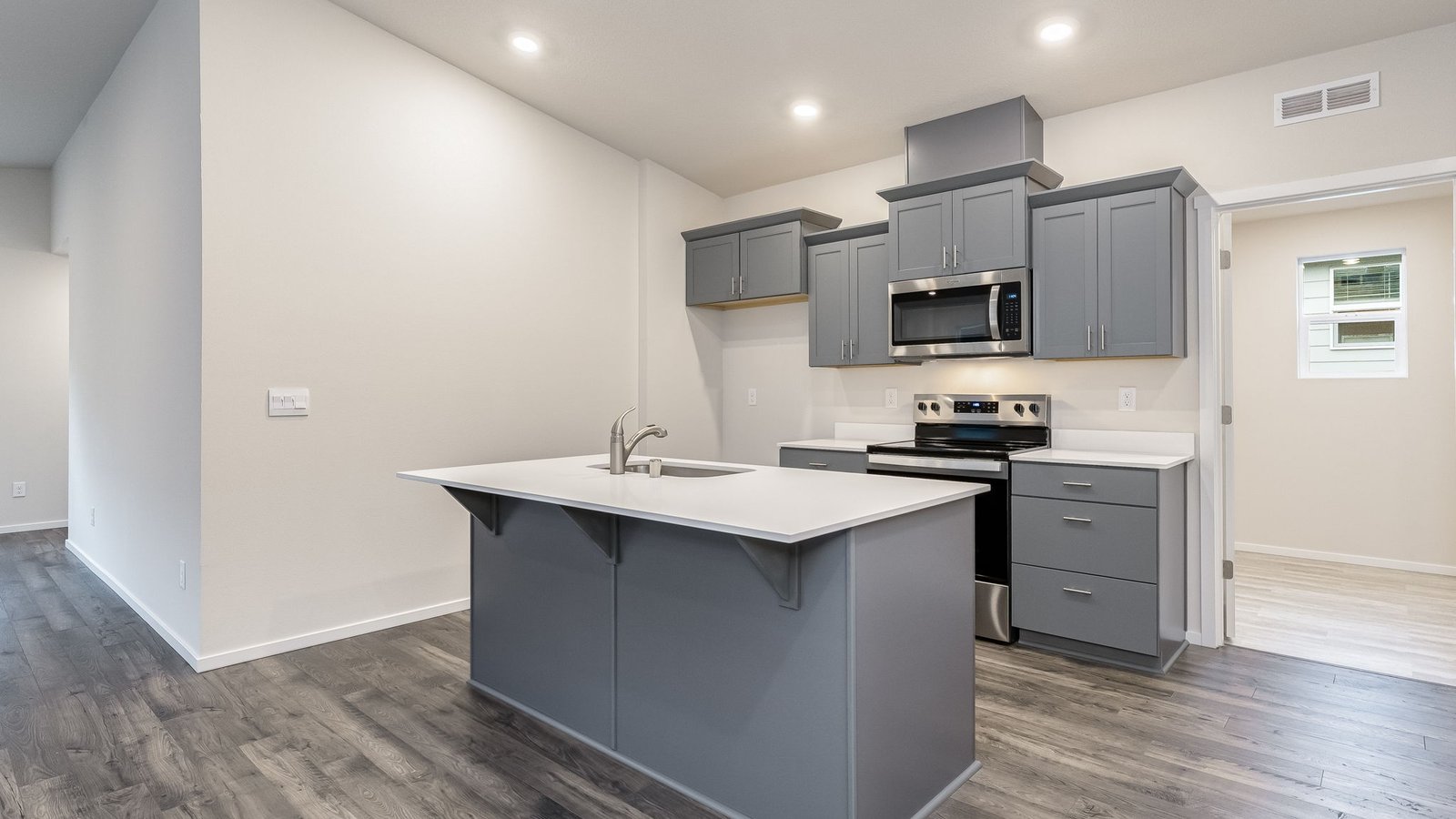 Kitchen with shaker cabinets, quartz counters, stainless steel appliances, pantry, and an island with a breakfast bar