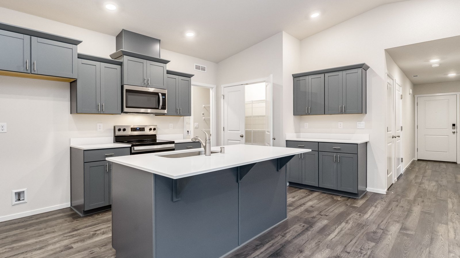 Kitchen with shaker cabinets, quartz counters, stainless steel appliances, pantry, and an island with a breakfast bar