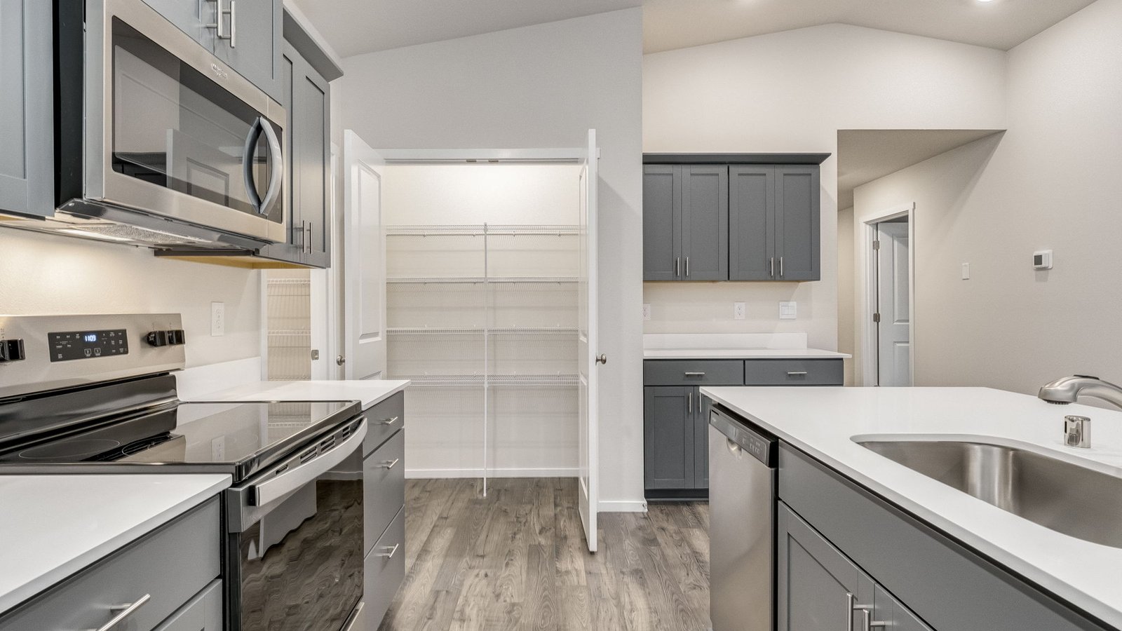 Kitchen with shaker cabinets, quartz counters, stainless steel appliances, pantry, and an island with a breakfast bar