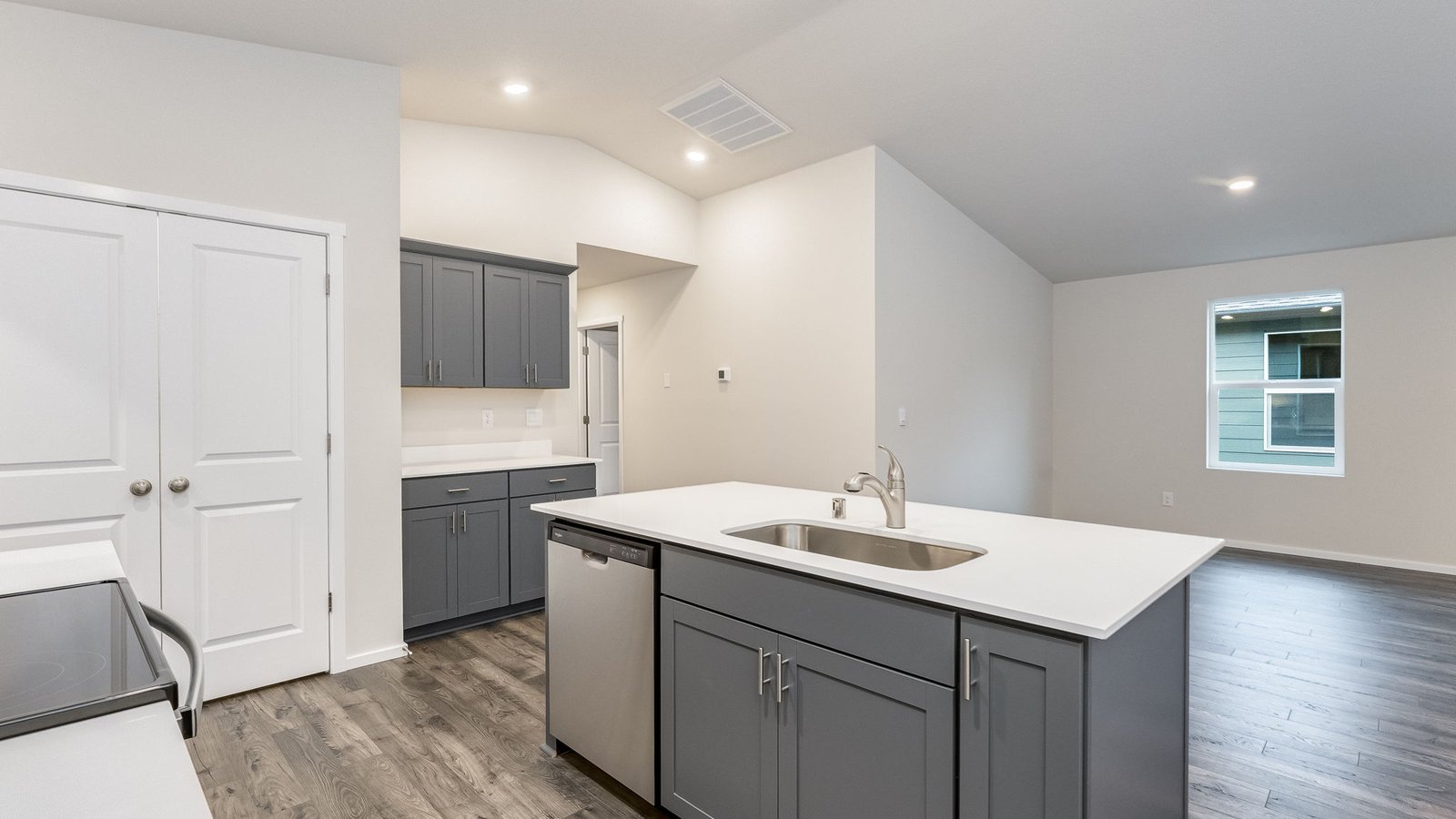 Kitchen with shaker cabinets, quartz counters, stainless steel appliances, pantry, and an island with a breakfast bar