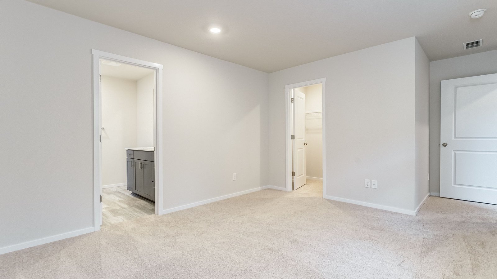 Primary bedroom with wall-to-wall carpet, a walk-in closet and an attached bathroom