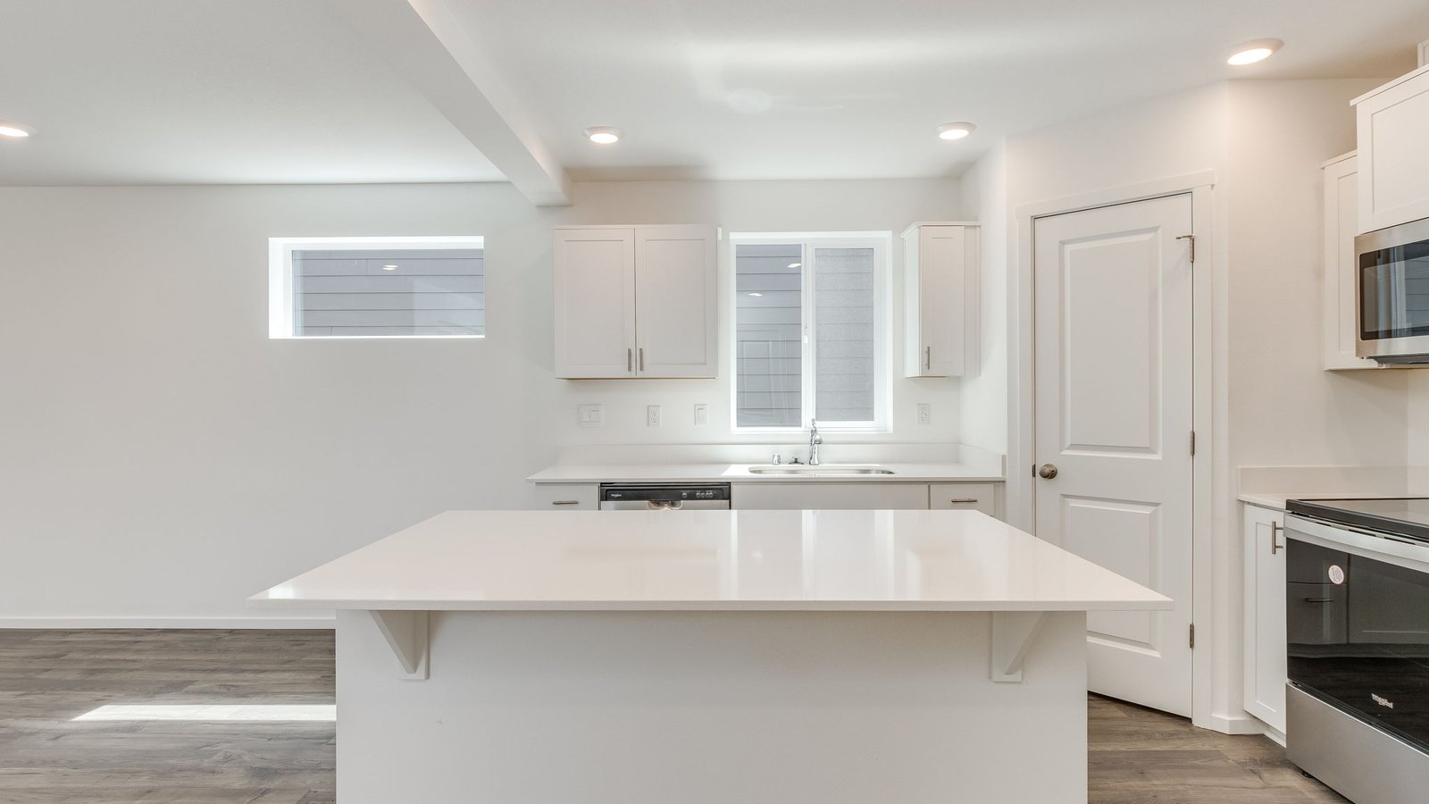 Kitchen with shaker cabinets, quartz counters, stainless steel appliances, pantry, and an island with a breakfast bar
