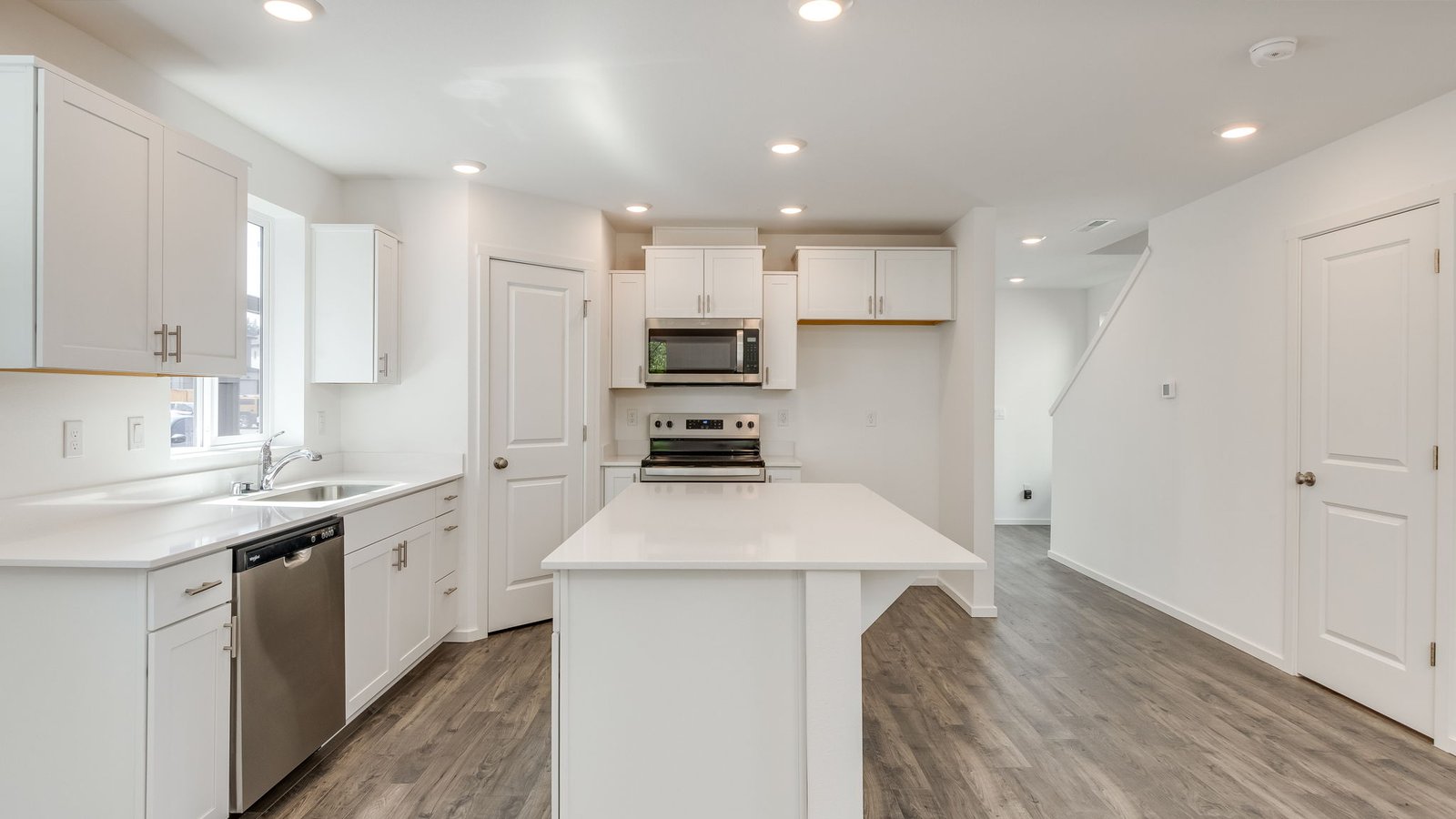 Kitchen with shaker cabinets, quartz counters, stainless steel appliances, pantry, and an island with a breakfast bar