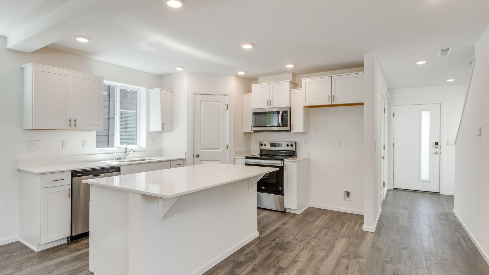 Kitchen with shaker cabinets, quartz counters, stainless steel appliances, pantry, and an island with a breakfast bar
