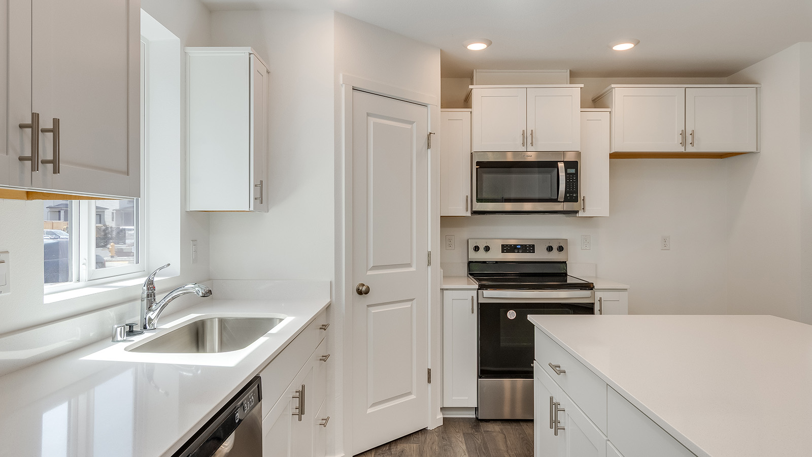 Kitchen with shaker cabinets, quartz counters, stainless steel appliances, pantry, and an island with a breakfast bar