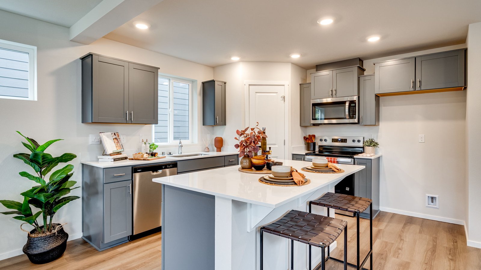 Kitchen with shaker cabinets, quartz counters, stainless steel appliances, pantry, and an island with a breakfast bar