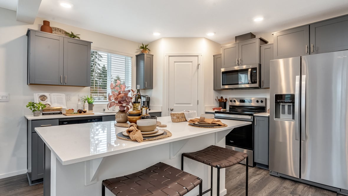 Kitchen with shaker cabinets, quartz counters, stainless steel appliances, pantry, and an island with a breakfast bar