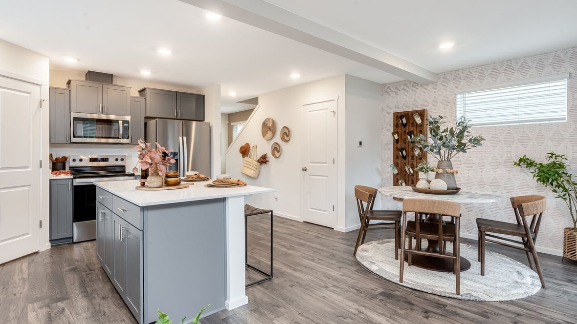 Kitchen with shaker cabinets, quartz counters, stainless steel appliances, pantry, and an island with a breakfast bar