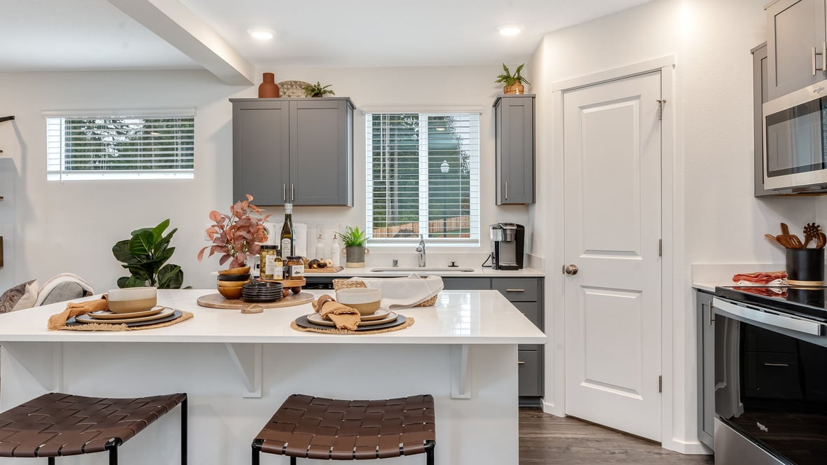 Kitchen with shaker cabinets, quartz counters, stainless steel appliances, pantry, and an island with a breakfast bar