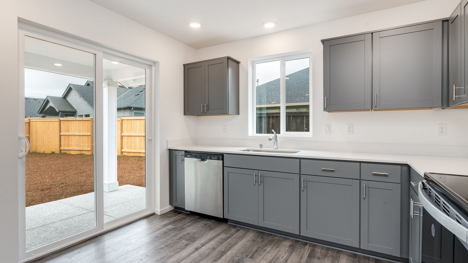 L-shaped kitchen with shaker cabinets, quartz counters, stainless steel appliances, and a pantry