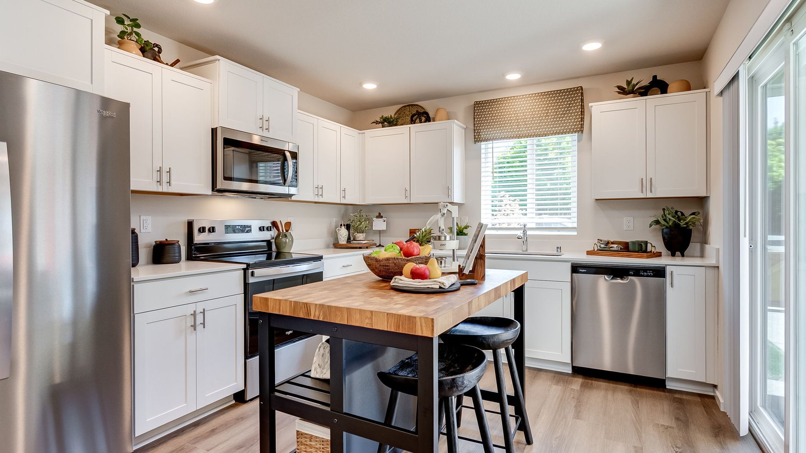 L-shaped kitchen with shaker cabinets, quartz counters, stainless steel appliances, and a pantry