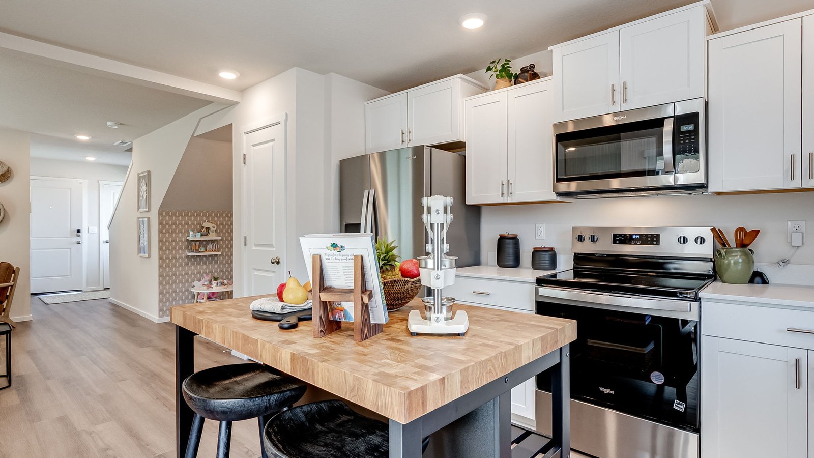 L-shaped kitchen with shaker cabinets, quartz counters, stainless steel appliances, and a pantry