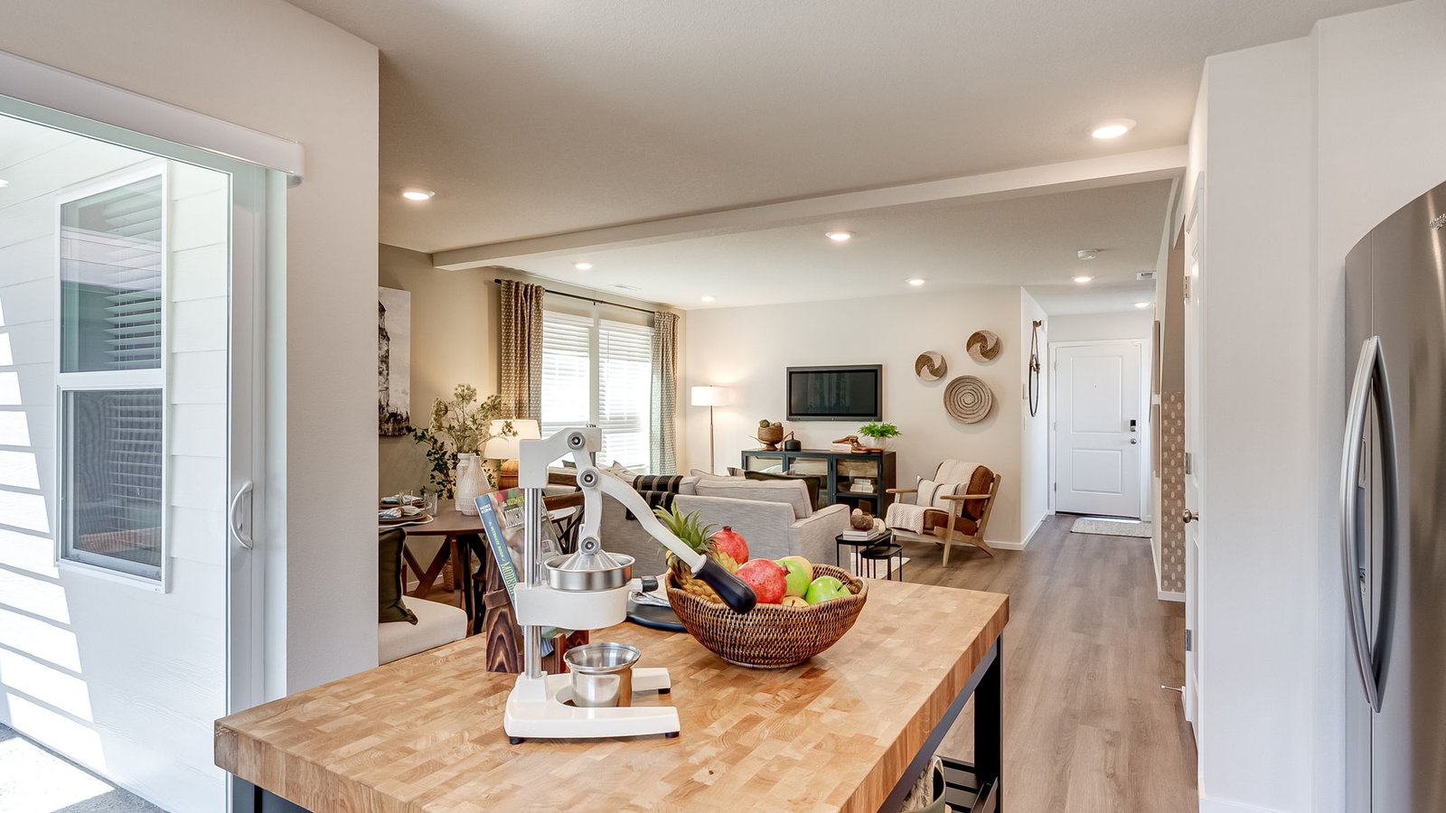 L-shaped kitchen with shaker cabinets, quartz counters, stainless steel appliances, and a pantry