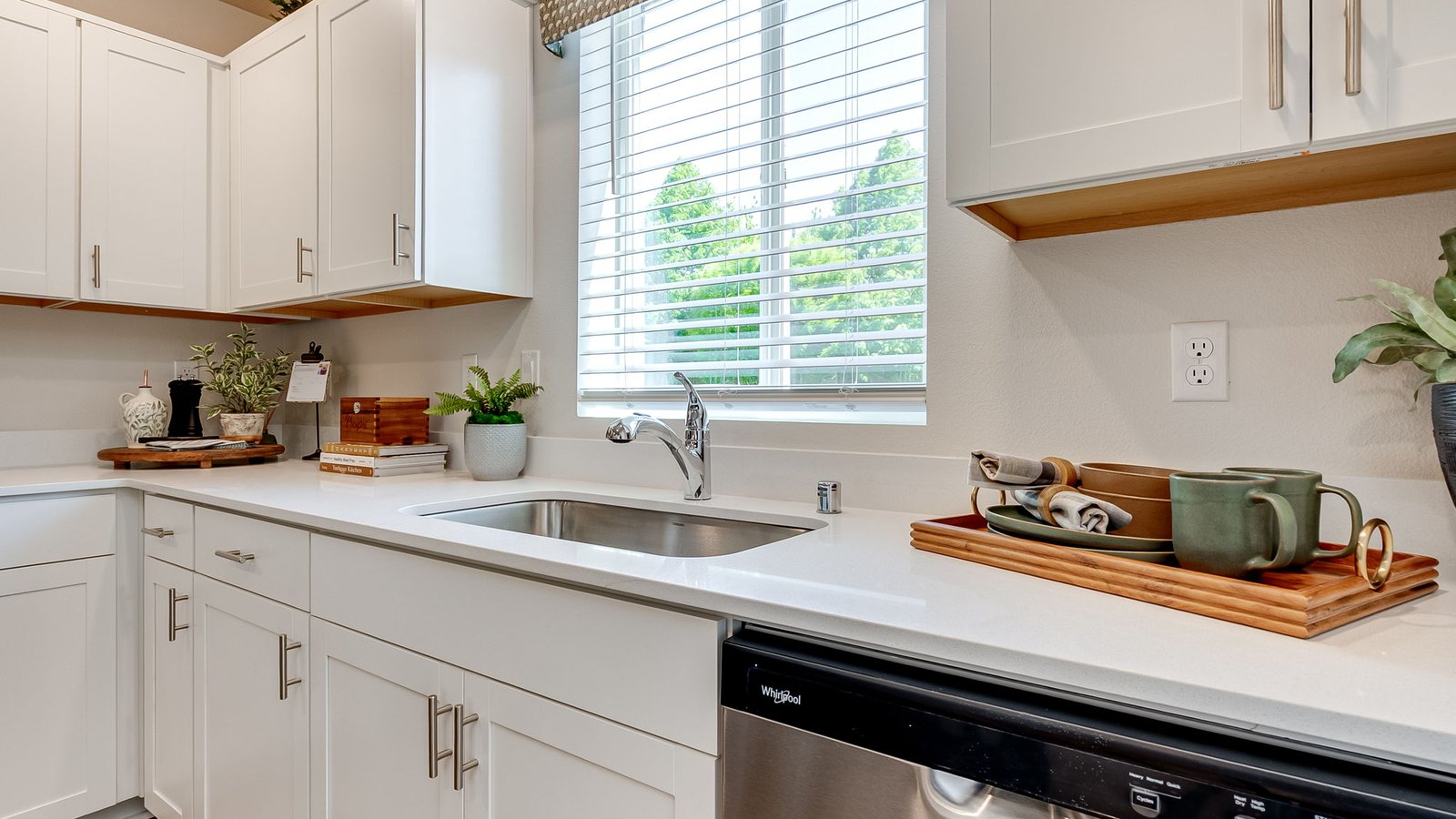 L-shaped kitchen with shaker cabinets, quartz counters, stainless steel appliances, and a pantry