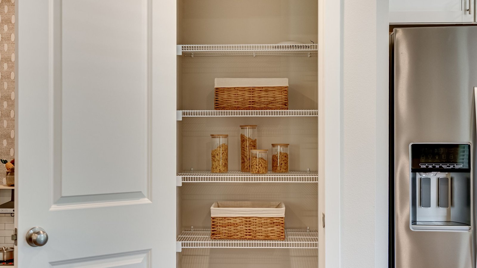 L-shaped kitchen with shaker cabinets, quartz counters, stainless steel appliances, and a pantry