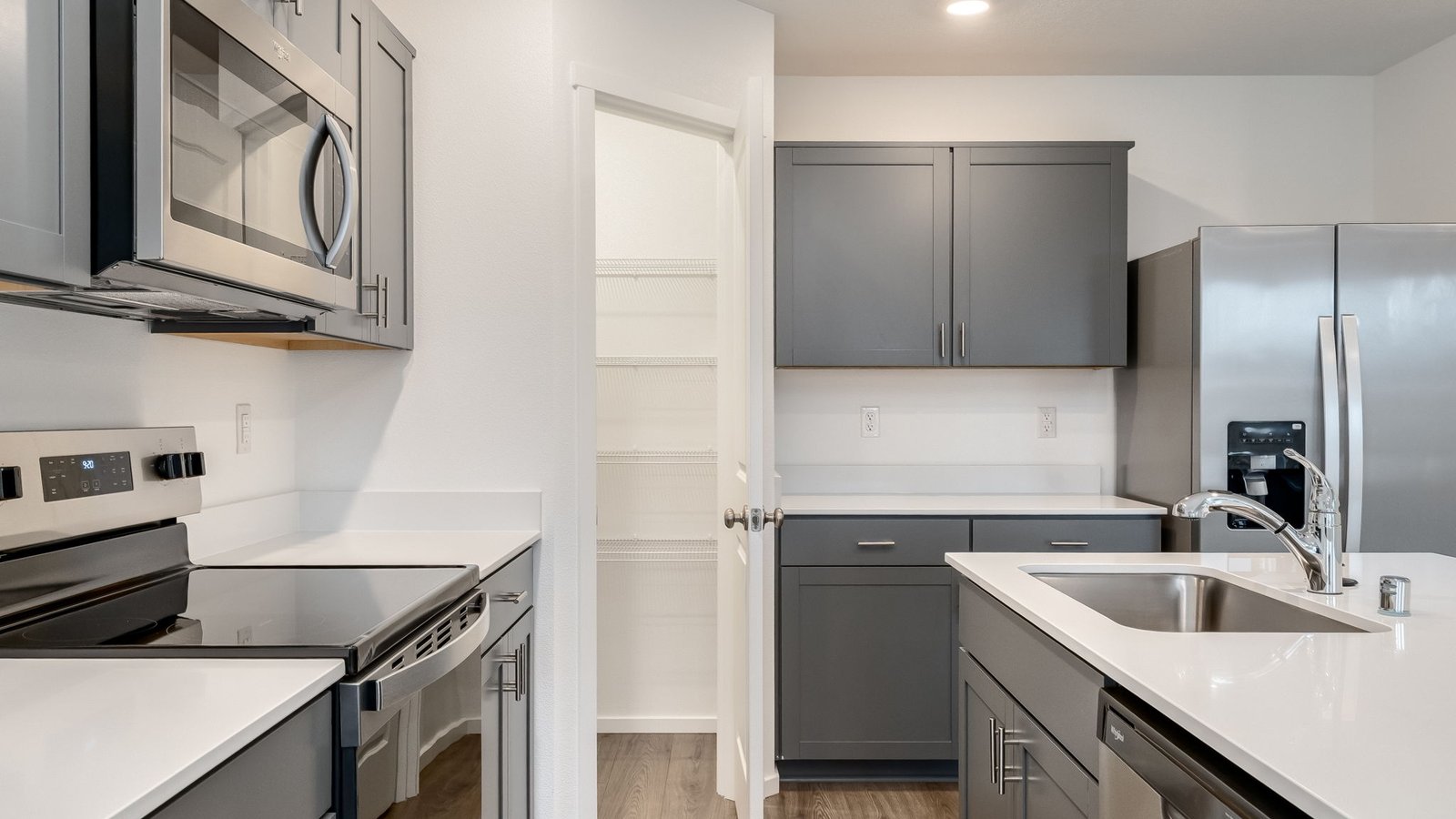 Kitchen with shaker cabinets, quartz counters, stainless steel appliances, pantry, and an island with a breakfast bar